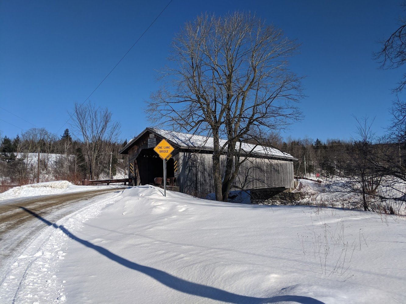 Historic Comstock Covered Bridge in winter with snow-covered landscape