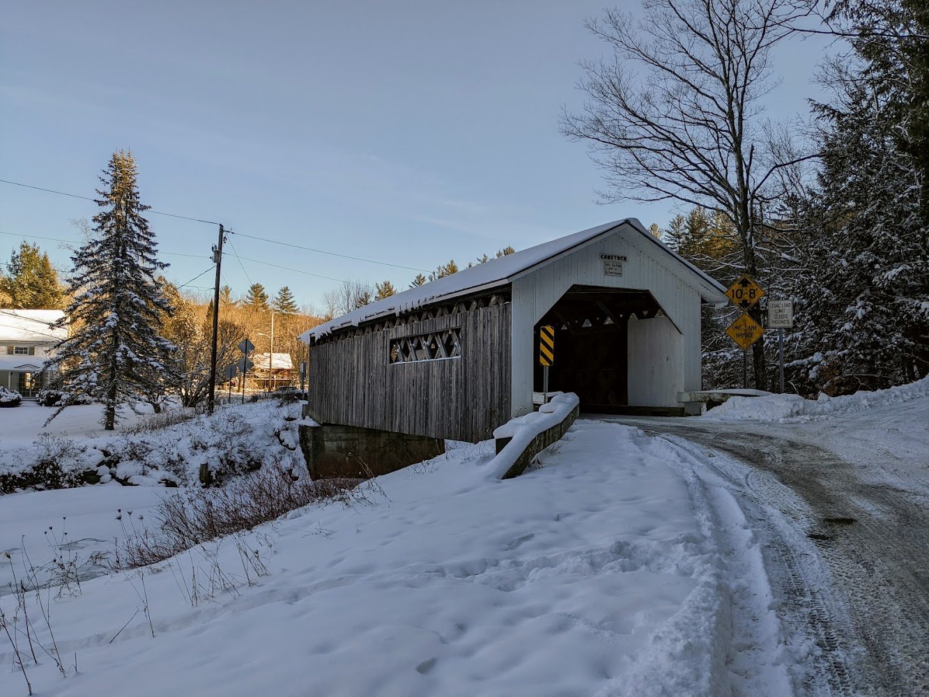 Historic Hopkins Covered Bridge in winter with snow-covered road and trees